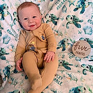 Jaxxon joined the competition — help win amazing prizes! baby, infant, child, smiling, portrait, lying_down, tan_romper, blanket, sea_turtles, turtle_pattern, milestone_photo, five_months, wooden_sign, indoors, soft_lighting, happy, cute, nursery, textile, photography