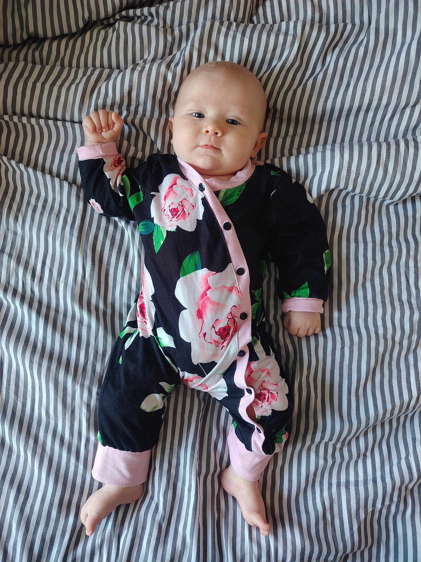 Maëve participe au concours pour gagner de l'argent avec cette photo : baby, infant, child, onesie, floral_pattern, bed, striped_bedding, foot, hand, face, sleepwear, pink, black, green, white, cute, lying_down, portrait, indoors, calm