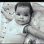 baby, infant, child, face, eyes, arms, curly_hair, smile, onesie, baby_mat, cartoon, measurement_scale, pacifier, cute, portrait, laying_down, indoors, soft_lighting, black_and_white, close_up