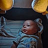 baby, infant, child, portrait, lying_down, awake, wide_eyed, facial_expression, clothing, onesie, teddy_bear, plush_toy, striped_blanket, blanket, indoor, ceiling_light, soft_toys, bed, cozy, photography