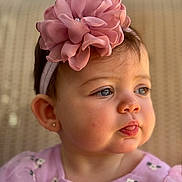 Amaia is registered to the contest to win money with this photo: baby, child, girl, face, headband, flower, pink, tongue, blue_eyes, earring, portrait, cute, close_up, soft_lighting, infant, clothing, expression, skin, background, sitting
