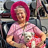 american_flag, blue_sky, bracelet, clouds, cute, dog_clothing, elderly_woman, handbag, happy, lace, outdoor, pet, pink_dress, pink_hat, portrait, small_dog, smiling, sunny_day, vehicle_seat, watch