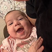 Jennie is registered to the contest to win money with this photo: baby, smile, infant, child, person, clothing, hand, face, happy, cute, patterned_background, sitting, pink, toddler, portrait, apparel, adult, hug, closeup, indoor