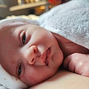 Florence is registered to the contest to win money with this photo: baby, close_up, sleepy, blanket, hat, infant, face, skin, hand, soft, resting, cute, newborn, indoors, warm, peaceful, portrait, headwear, toddler, cozy