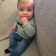 Achille participe au concours pour gagner de l'argent avec cette photo : baby, bodypart, clothing, coat, couch, cushion, face, finger, furniture, hand, head, homedecor, hosiery, jeans, pants, person, photography, portrait, sitting, sock