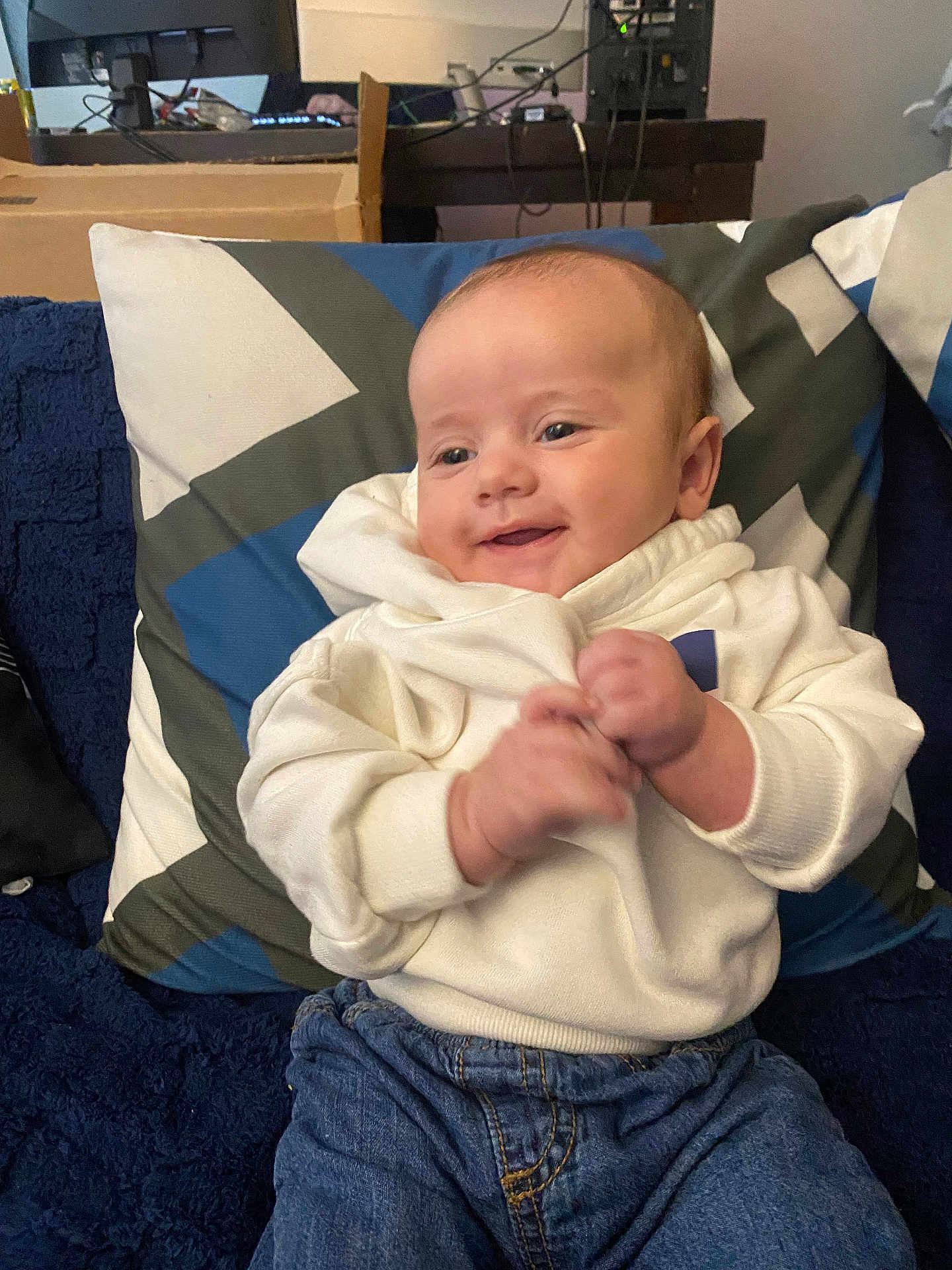 Leonardo joined the competition — help win amazing prizes! baby, child, smiling, white_hoodie, blue_jeans, pillow, blanket, indoor, couch, clapping, happy, cute, face, infant, person, seated, casual_clothing, home, furniture, relaxed