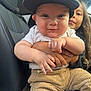 baby, child, car_seat, clothing, cap, corduroy_pants, cuddling, cute, face, family, holding, infant, inside_car, person, portrait, smiling, sibling, toddler, young_child, window