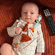 Raphaël participe au concours pour gagner de l'argent avec cette photo : baby, bib, blanket, child, clothing, couch, cute, face, foot, fox_pattern, hand, home, indoor, infant, onesie, portrait, relaxing, remote_control, smiling, soft_toy