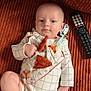baby, bib, blanket, child, clothing, couch, cute, face, foot, fox_pattern, hand, home, indoor, infant, onesie, portrait, relaxing, remote_control, smiling, soft_toy