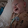 baby, bed, blue_toy, child, cozy, cute, expression, face, happy, indoors, infant, jurassic_park, lying_down, onesie, person, pillow, plush_toy, sleepwear, smiling, soft_lighting