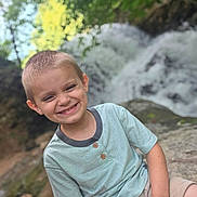 Zeke joined the competition — help win amazing prizes! child, boy, smiling, outdoor, nature, waterfall, greenery, rock, happy, portrait, short_hair, casual_clothing, summer, daylight, scenic, adventure, youth, playful, relaxed, environment