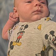 Remington joined the competition — help win amazing prizes! apparel, baby, blue_background, cartoon, child, clothing, cute, face, hand, head, infant, lying_down, mickey_mouse, newborn, onesie, person, portrait, relaxed, skin, soft