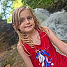 background_blur, blonde_hair, casual_clothing, child, cute, daylight, girl, greenery, happy, nature, outdoor, portrait, posing, red_tank_top, scenic, smiling, summer, unicorn_graphic, waterfall, young