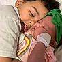 Joseph is registered to the contest to win money with this photo: baby, child, newborn, hugging, toddler, green_headband, rainbow_shirt, sleeping_baby, smiling_child, family, love, cuddling, closeup, indoor, soft_lighting, cute, infant, person, affection, white_clothing