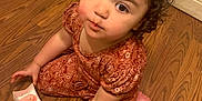 Bailey is registered to the contest to win money with this photo: toddler, child, sitting, curly_hair, brown_eyes, pink_cookies, wooden_floor, indoor, cute, pout, outfit, floral_pattern, box, snack, person, portrait, baby, small_hands, flooring, expression