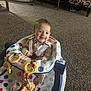 baby, baby_walker, carpet, child, colorful, comfort, cute, face, furniture, happy, home, indoors, infant, living_room, pajamas, person, play, seat, smiling, toy