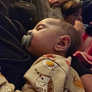 Ronan is registered to the contest to win money with this photo: baby, blanket, child, clothing, comfort, couch, cozy, face, family, head, indoor, milk_carton_print, onesie, pacifier, person, portrait, resting, sleeping, soft_lighting, young_child