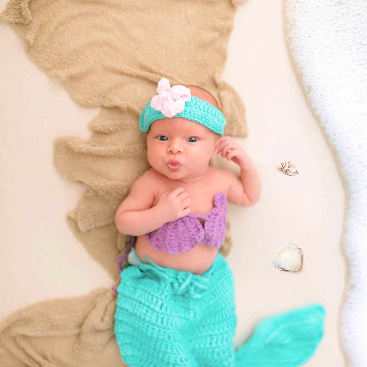 Raelynn is registered to the contest to win money with this photo: baby, mermaid, costume, headband, flower, seashells, fabric, foam, puckered_lips, lying_down, purple, turquoise, cute, infant, portrait, hand_near_face, soft_texture, playful, ocean_theme, decorative