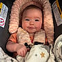 baby, infant, car_seat, blanket, pink, face, smile, child, cushion, clothing, soft_texture, headrest, happy, portrait, close_up, indoor, cute, warm, resting, newborn