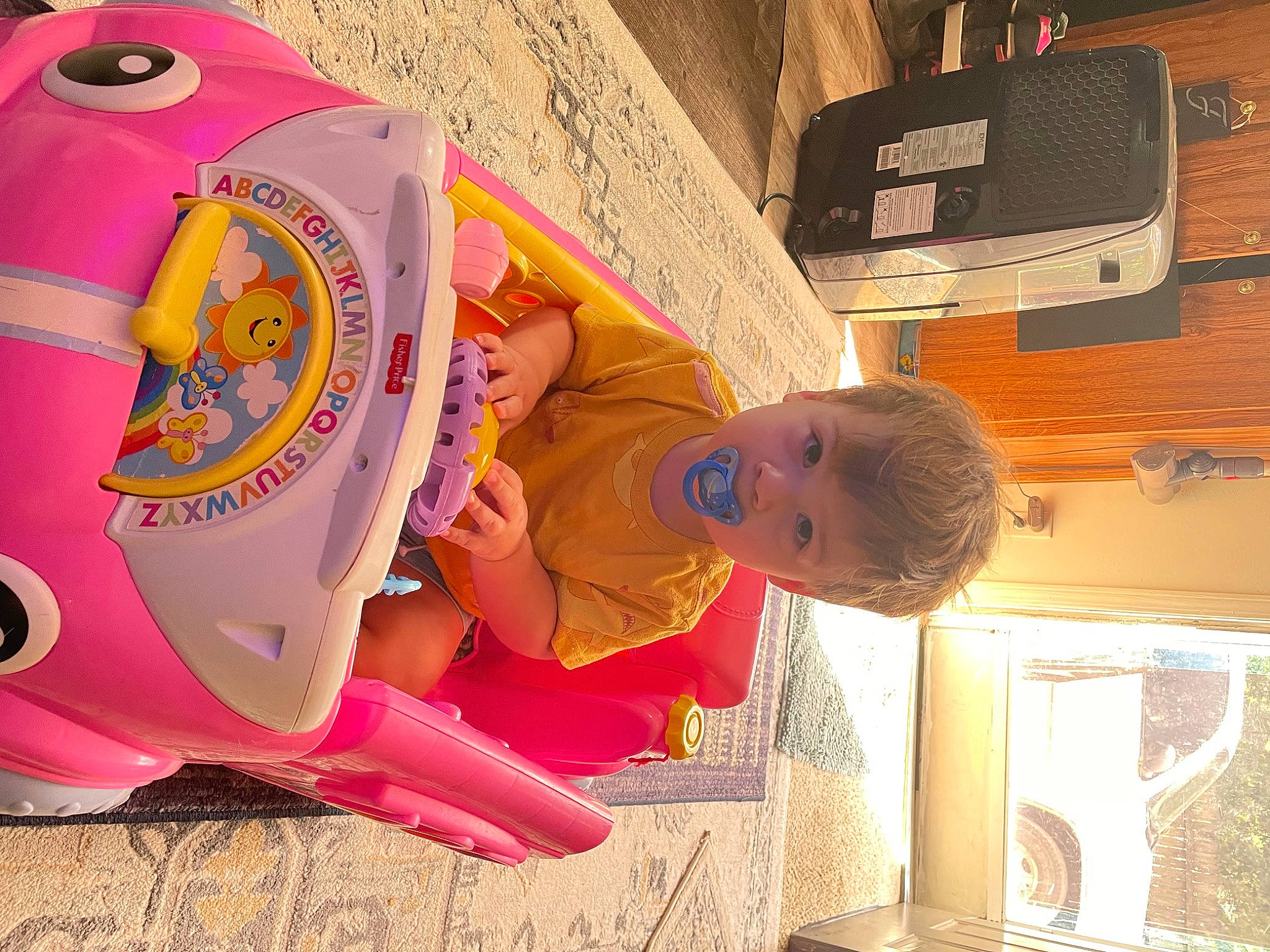 Peyton is registered to the contest to win money with this photo: art, baby, baby_products, ceiling, child, flooring, font, fun, leisure, magenta, person, personal_protective_equipment, play, recreation, room, tire, toddler, vehicle_door, visual_arts, wheel