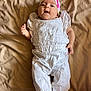 baby, beige_blanket, child, cute, face, fashion, footwear, hand, happy, headband, indoors, infant, lying_down, pink_bow, portrait, smiling, soft_lighting, textile, white_clothing, young_child