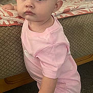 Brooklyn is registered to the contest to win money with this photo: toddler, child, pink_shirt, colorful_pants, standing, indoor, carpet, couch, blanket, curious, young_child, furniture, home, person, face, hand, expression, living_room, clothing, floor