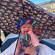 Jesse joined the competition — help win amazing prizes! baby, blanket, blue_sky, bottle, chewing, child, clothing, colorful, cowboy_toy, dinosaur_hat, hand, hat, outdoor, person, seat, smiling, sunny, teething_toy, toy, umbrella