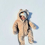 Noah is registered to the contest to win money with this photo: baby, snow, snowsuit, winter_clothing, hat, child, outdoor, snowy, cute, cold_weather, fuzzy, one_person, lying_down, infant, face, footwear, gloves, warm_clothing, winter, frozen