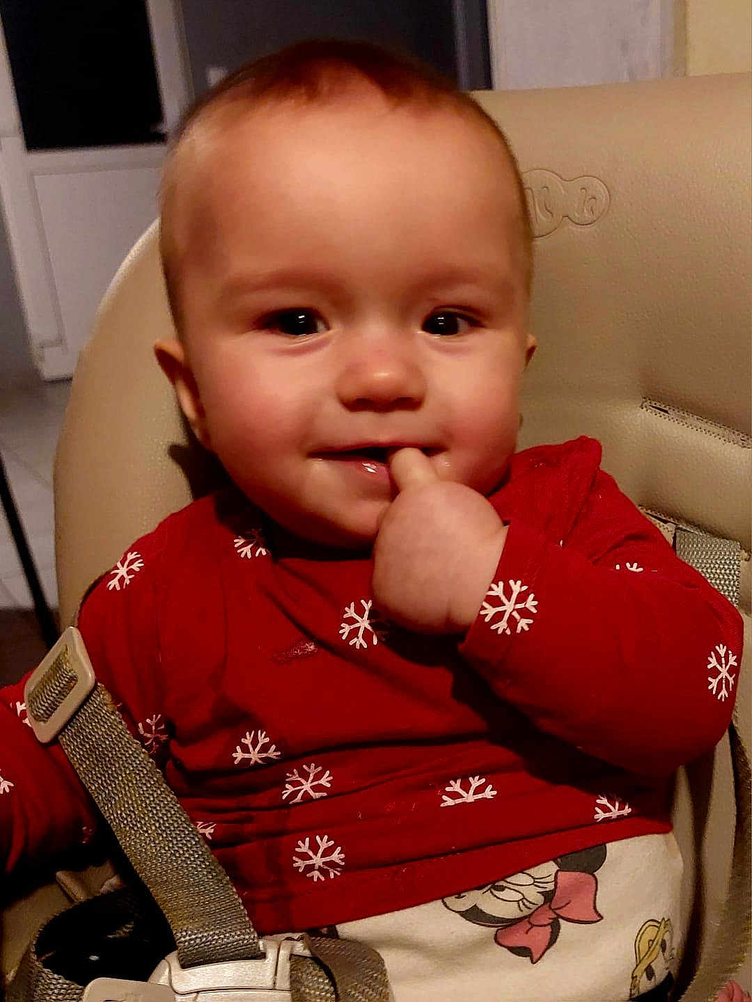 Syana participe au concours pour gagner de l'argent avec cette photo : baby, child, high_chair, red_shirt, snowflake_pattern, smiling, finger_in_mouth, indoor, seatbelt, cute, face, human, young_child, holiday_theme, playful, clothing, person, portrait, cheerful, infant