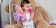 Athena is registered to the contest to win money with this photo: baby, child, toddler, teddy_bear, plush_toy, pacifier, backpack, butterfly, pajamas, floor, carpet, wall, indoor, cute, smile, playful, toy, footwear, person, home