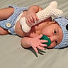 baby, infant, child, lying_down, bed, indoors, crocheted_clothing, elephant_costume, blue_hat, stuffed_toy, knitted_toy, pacifier, white_diaper, bare_feet, portrait, close_up, smiling, playful, textile, home