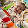 Ali joined the competition — help win amazing prizes! baby, smiling, infant, blanket, play_mat, toy, rainbow, colorful, face, happy, indoors, floor, carpet, clothing, cute, child, person, cozy, teddy_bear, soft