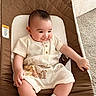 baby, infant, child, smiling, baby_seat, clothing, socks, carpet, bed, indoor, cute, relaxed, person, portrait, young_child, comfortable, soft_light, home, seat, resting