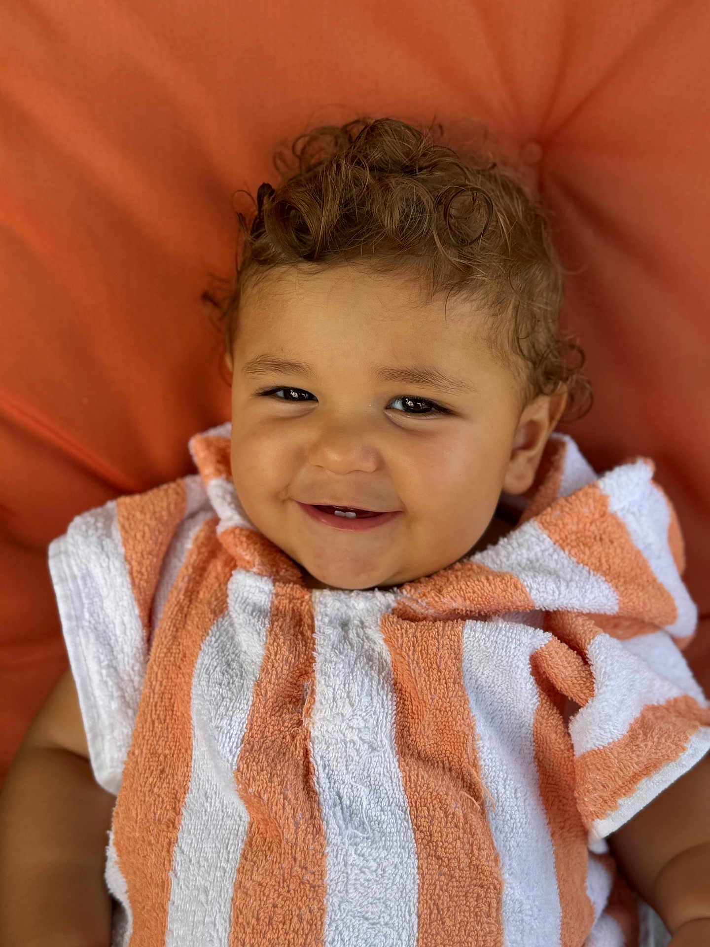 Paul participe au concours pour gagner de l'argent avec cette photo : toddler, child, smiling, curly_hair, towel, orange, white, striped, portrait, close_up, happy, cute, baby, face, skin, eyes, person, indoors, cozy, background