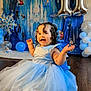 balloons, birthday, blue_dress, castle_backdrop, celebration, child, curly_hair, decoration, disney, dress, floor, frozen_theme, happy, indoor, party, person, princess_dress, smiling, snowflake, toddler