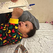 Bryson joined the competition — help win amazing prizes! baby, infant, child, pacifier, blanket, colorful_clothing, pen, paper, bed, texture, indoors, curious, lying_down, holding, face, head, hand, toy, accessory, playful