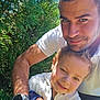child, man, smile, outdoor, greenery, sunlight, shadow, happy, portrait, nature, casual_clothing, watch, daylight, closeup, family, affection, people, human, together, friendly