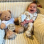 Rhys is registered to the contest to win money with this photo: baby, teddy_bear, plush_toy, couch, pajamas, smiling, milestone_sign, infant, cozy, soft_texture, child, happy, cream_color, sitting, cute, indoor, furniture, celebration, joyful, portrait