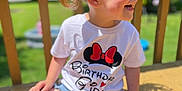Myra joined the competition — help win amazing prizes! birthday, casual_clothing, celebration, child, curly_hair, daylight, girl, hair, happy, headband, minnie_mouse, outdoor, playful, purple_socks, shorts, sitting, smiling, sunlight, tshirt, wooden_deck