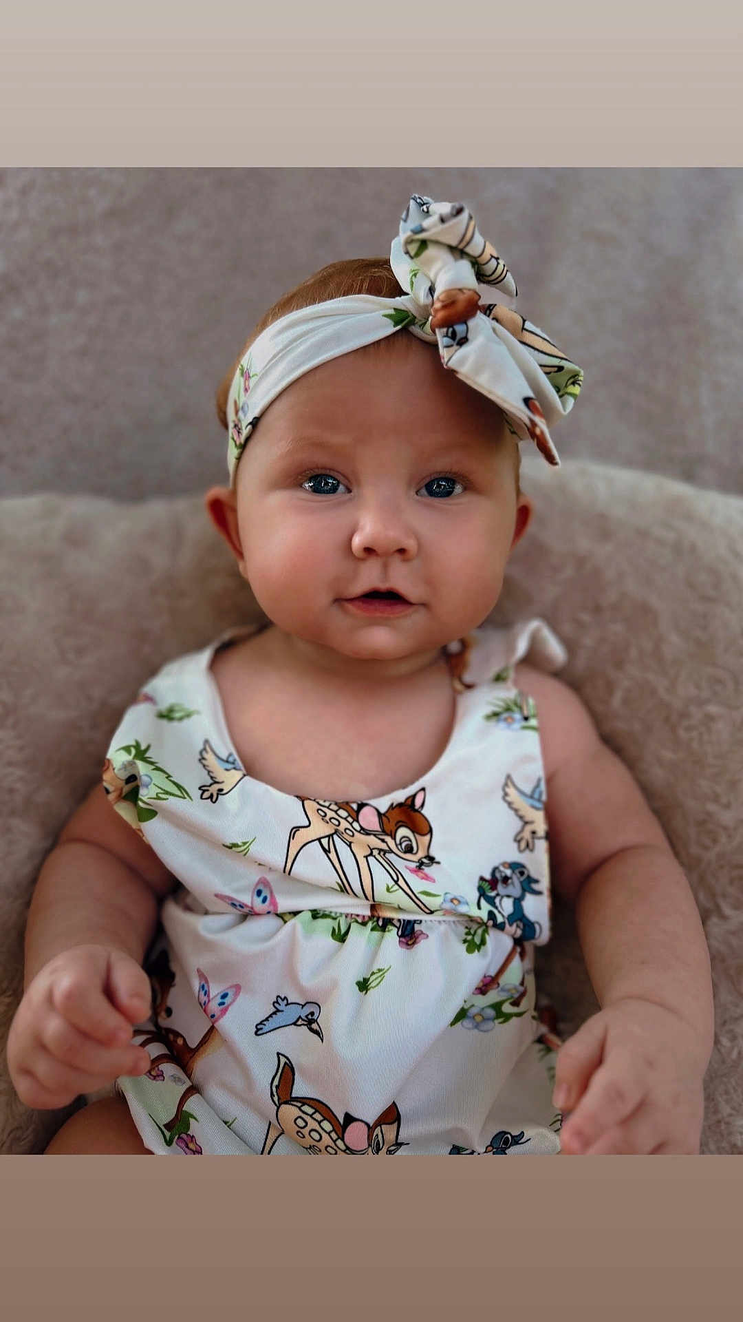 Kimberly joined the competition — help win amazing prizes! baby, child, headband, bow, dress, animal_print, sitting, cushion, soft_texture, cute, portrait, indoor, face, eyes, hand, infant, clothing, person, adorable, closeup