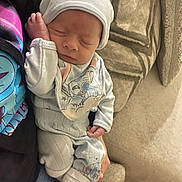 November is registered to the contest to win money with this photo: baby, newborn, sleeping, hat, clothing, sock, person, hand, couch, fabric, pattern, infant, resting, cozy, cute, portrait, indoors, comfort, wrapped, peaceful