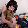 woman, person, puppy, dog, brown_dog, pet, cuddling, hugging, sitting, bed, blanket, plaid, toy, squeaky_toy, dog_bowl, indoor, bedroom, portrait, happy, animal