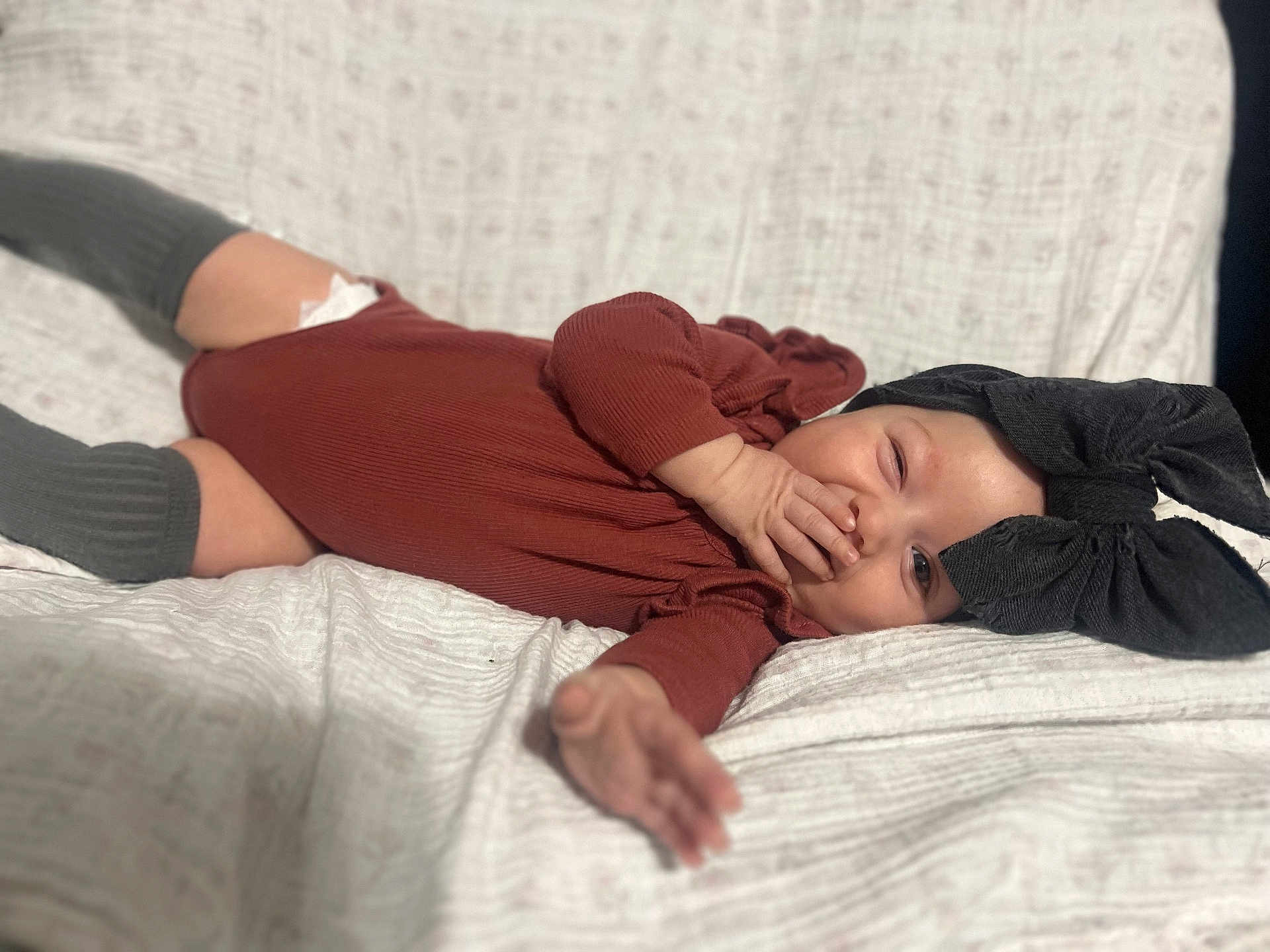 Everley joined the competition — help win amazing prizes! baby, infant, smile, black_bow, headband, rust_colored_clothing, blanket, lying_down, hand, cute, child, cozy, portrait, happy, indoors, soft_texture, toddler, fashion, warm_colors, playful