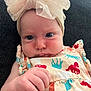 baby, infant, headband, bow, dress, colorful, pattern, horses, hand, face, skin, couch, indoor, portrait, child, curious, closeup, soft_light, clothing, young