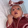 baby, infant, velvet_clothing, headband, bow, blanket, pink, soft_texture, curious, face, skin, hand, lying_down, indoors, cute, expression, child, newborn, portrait, closeup