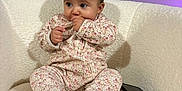 Shëlby a rejoint le concours — aidez-le/la à gagner de superbes lots ! baby, child, onesie, floral_pattern, hand_in_mouth, curious, indoor, white_chair, cozy, smartphone, modern_interior, helmet, wall_art, window, seated, cute, soft_texture, infant, portrait, cozy_clothing
