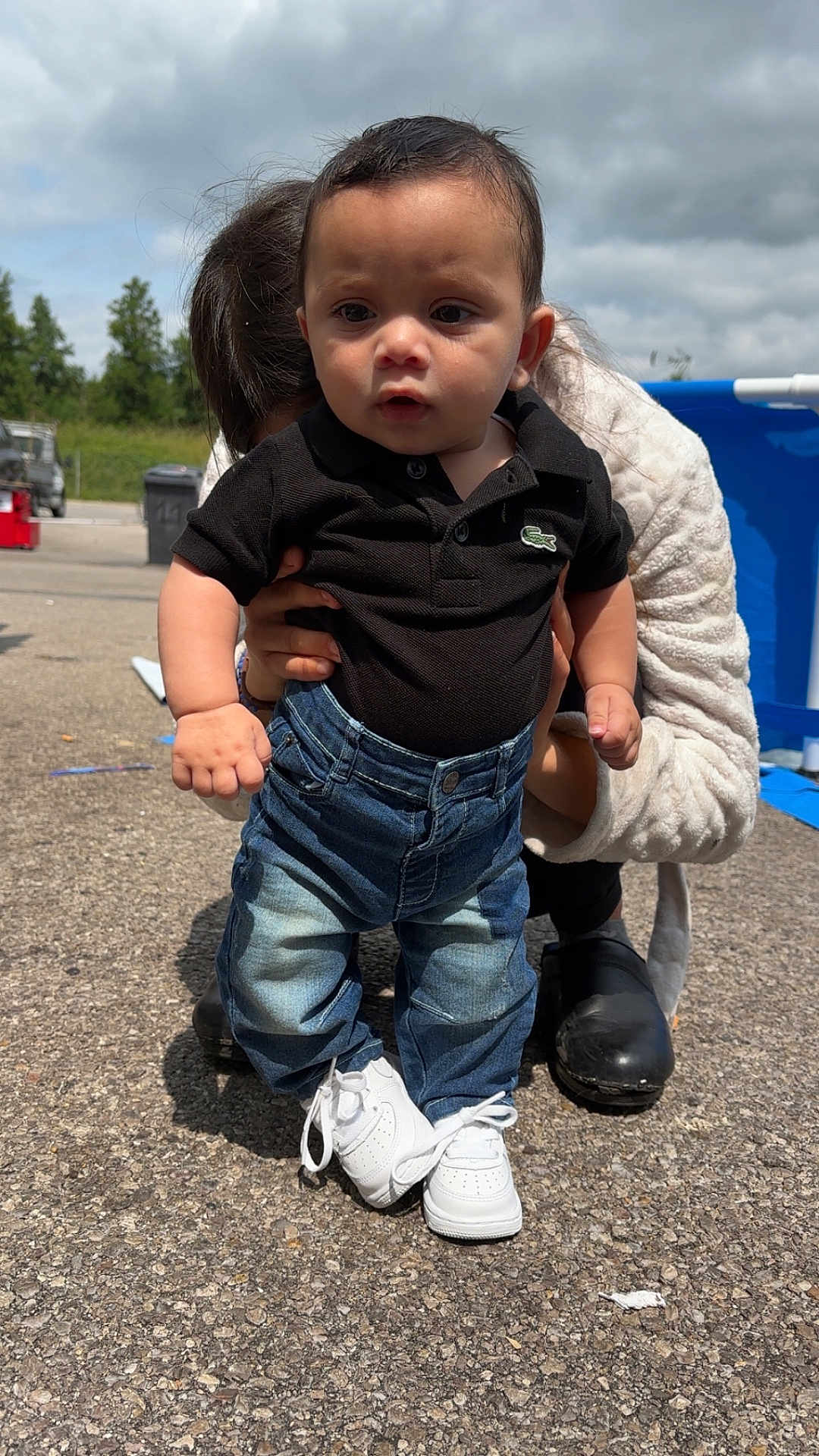 Reyden a rejoint le concours — aidez-le/la à gagner de superbes lots ! baby, black_polo, blue_pool, casual_clothing, child, cloudy_sky, daylight, feet, greenery, hands, helping_hand, jeans, outdoor, pavement, person_supporting, shoes, standing, toddler, white_sneakers, young_child