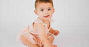 Giada joined the competition — help win amazing prizes! baby, child, toddler, girl, pink_dress, number_one, white_background, sitting, barefoot, portrait, cute, smiling, short_hair, blue_eyes, studio_photo, minimalistic, innocent, playful, hand, floor