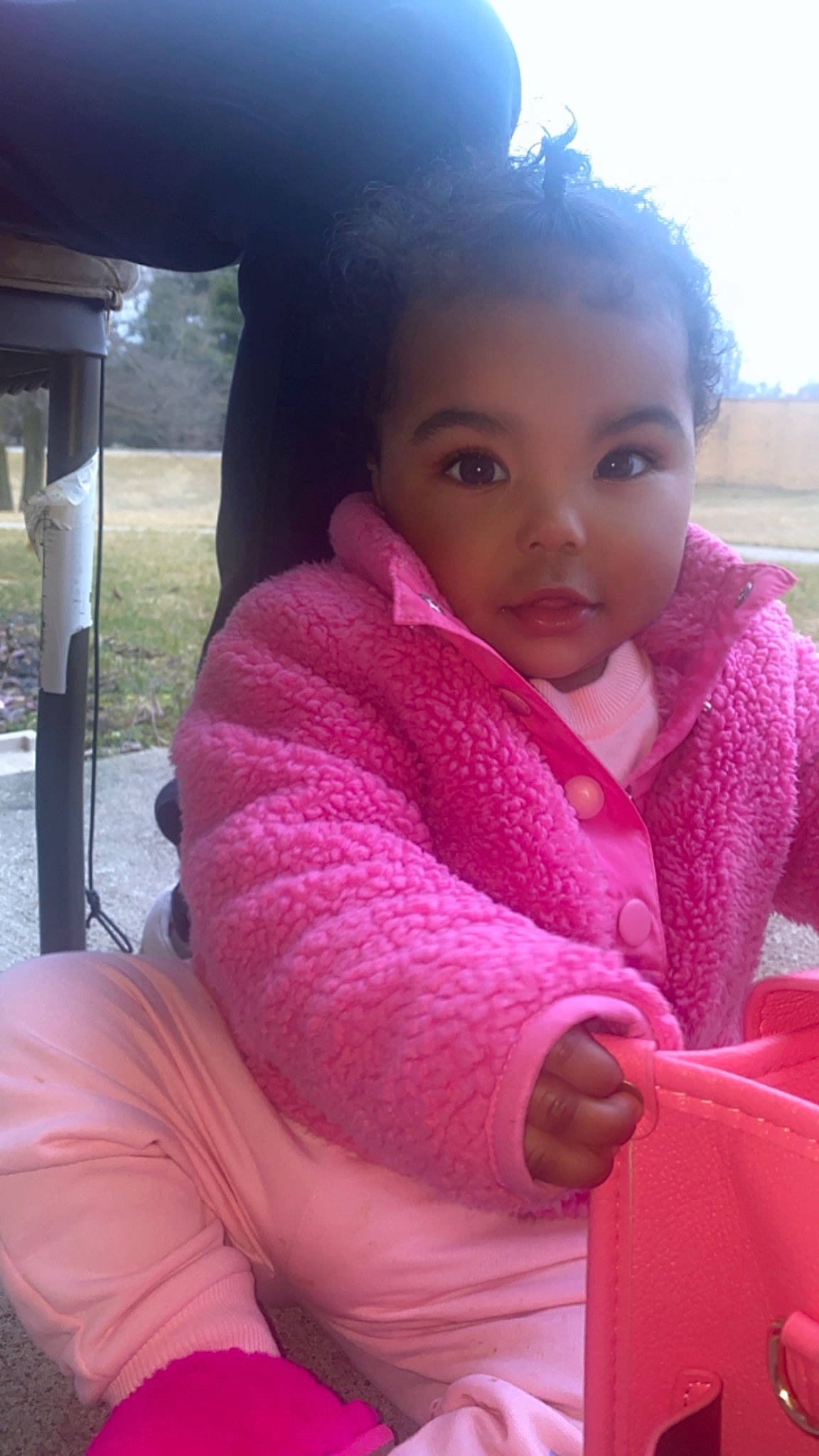 Khalya is registered to the contest to win money with this photo: baby_toddler_clothing, black_hair, cheek, child, comfort, eyebrow, eyelash, family_car, grass, happy, lip, magenta, nose, person, pink, plant, sitting, skin, toddler, tree