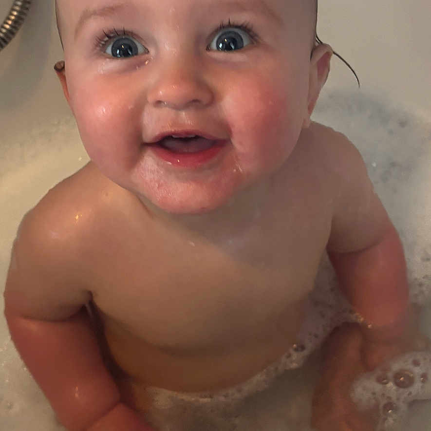 Amelia is registered to the contest to win money with this photo: baby, bath, blue_eyes, bubbles, child, cute, face, foam, hand, happy, head, indoors, infant, person, playful, skin, smile, tub, water, wet